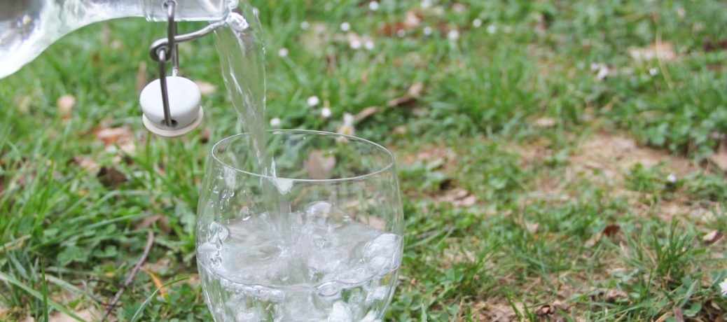 Foto eines Kristallglases, in das Wasser eingegossen wird